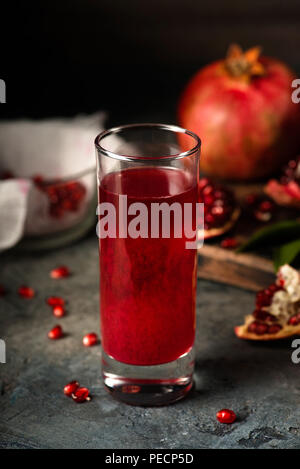 Glas Granatapfelsaft. Obst mit Getreide und Blätter auf dem Tisch. Machen. Dunkle Moody. Stockfoto