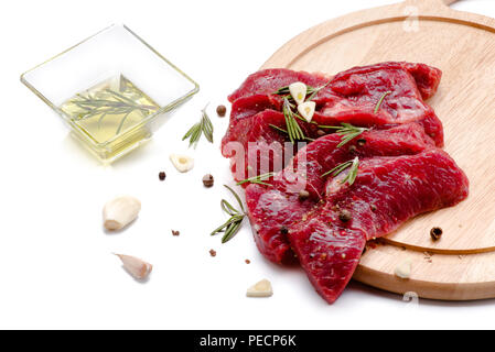 Stücke von Fleisch mit Knoblauch und Rosmarin auf weißem Hintergrund. Rohes Rindfleisch. Stockfoto