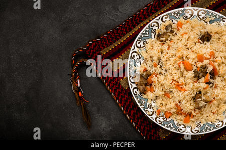 Pilav auf Platte mit orientalischen Ornament. Zentralasiatische Küche - Plov. Ansicht von oben. Stockfoto