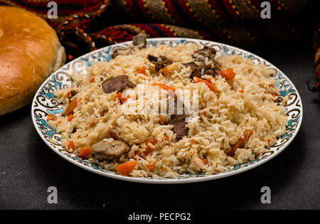 Pilav auf Platte mit orientalischen Ornament und traditionellen asiatischen Brot - churek. Plov. Stockfoto