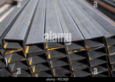 Square flat-rolled pipe metal profile in packs at the warehouse of metal products. Weathered metals profiles for construction. Metal corrosion Stockfoto