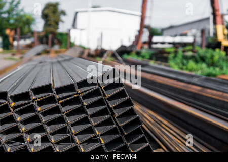 Square flat-rolled pipe metal profile in packs at the warehouse of metal products. Weathered metals profiles for construction. Metal corrosion Stockfoto