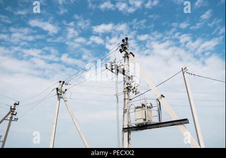 Elektriker Verkabelung Kabel über Power Line. Strom Konzept, in der Nähe von Hochspannungsleitungen. Hohe Spannung des elektrischen Getriebes pylon Turm Stockfoto