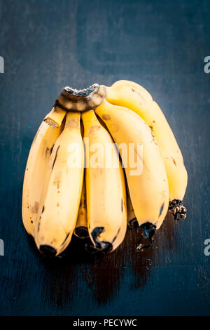 Nahaufnahme eines Bündel Bananen auf einer hölzernen Oberfläche in dunklen Gothic Farben. Stockfoto