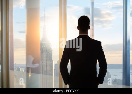 Geschäftsmann auf der Suche Fenster unten auf Stadt Stockfoto