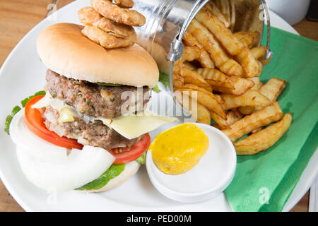 Hausgemachte doppel Hamburger und Käse mit einem Eimer/Eimer Kartoffelchips/Pommes und englischer Senf Stockfoto
