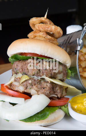 Hausgemachte doppel Hamburger und Käse mit einem Eimer/Eimer Kartoffelchips/Pommes und englischer Senf Stockfoto