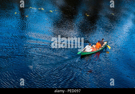 Auf 3 Menschen in einem Kanu auf einem blauen Fluss Stockfoto