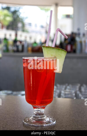 Red Cocktail mit einem Stück Melone an der Bar Stockfoto