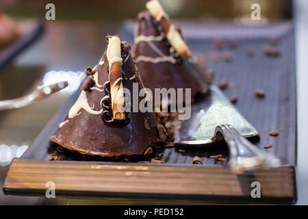 Schokoladenkuchen mit weißer Schokolade rasieren auf silbernem Tablett Stockfoto