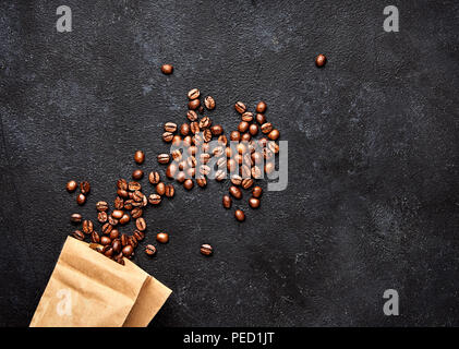 Kaffeebohnen auf Schwarz konkreten Hintergrund mit Papier. Ansicht von oben Stockfoto