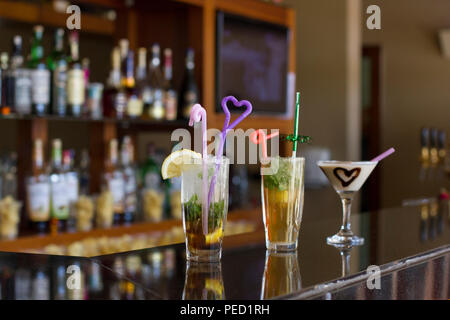 Drei Cocktails an der Bar - Mojito mit Eis und Stroh, Pina Colada mit Schokolade Herz Stockfoto