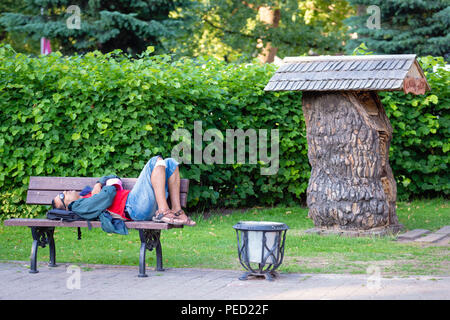 RIGA. Lettland. - Juli 08, 2018: Im Park auf der Bank schläft ein Mann. Stockfoto
