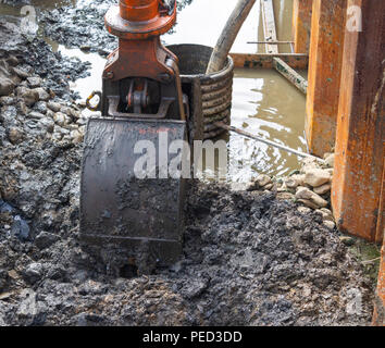 Mechanische Bagger mit Schaufel Aushub eines Grabens auf einer Baustelle. Stockfoto