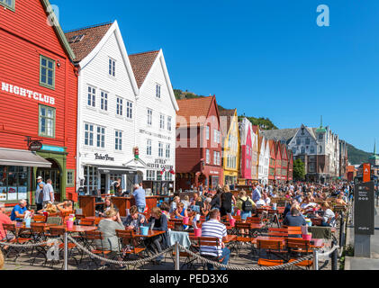 Bergen, Norwegen. Cafés und Bars vor traditionellen Holzgebäuden im historischen Stadtteil Bryggen, Hafen Vagen, Bergen, Norwegen Stockfoto