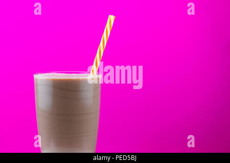 Schokolade Milchshake in einem Glas mit Strohhalm gegen ein helles Rosa Hintergrund mit Kopie Raum Stockfoto