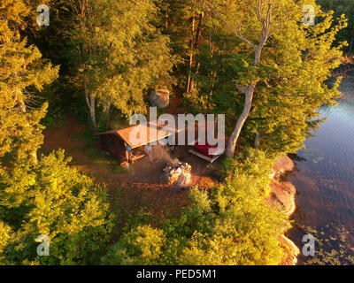 Antenne drone Bild eines Log cabin Lean - zu Schutz und Lagerfeuer auf einem See in den Adirondack Mountains. Aus der Vogelperspektive einen am Meer gelegenen Campingplatz Stockfoto