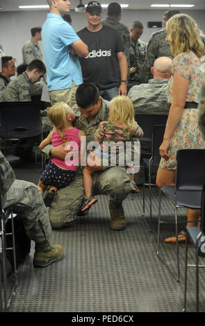 Ein Wartungsspezialist der 5th Maintenance Squadron der US Air Force hält seine Kinder am 1. August 2015 auf der Minot Air Force Base in North Dakota fest, nachdem er vom Training der Red Flag 15-3 auf der Nellis Air Force Base in Nevada zurückgekehrt war. Der Airman ist der 69th Bomb Squadron zugeordnet, die die B-52H Stratofortress betreibt, ein strategischer Langstreckenbomber mit Unterschallantrieb und acht Turbofan-Triebwerken für nukleare und konventionelle Missionen. Stockfoto