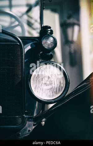 Lettland. Riga. Das stilisierte Bild eines Oldtimer mit einem großen Scheinwerfer und Kühlergrill auf der Straße mit einer Laterne Stockfoto