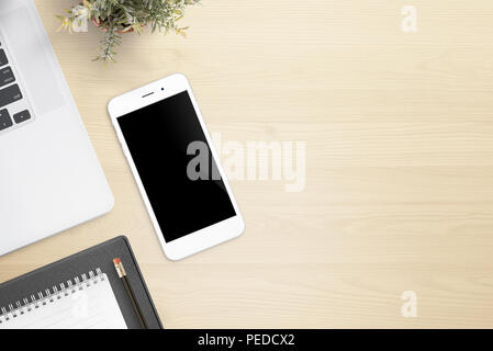 Schreibtisch mit Handy, Laptop, pad, Bleistift und Anlage auf Sie. Stockfoto