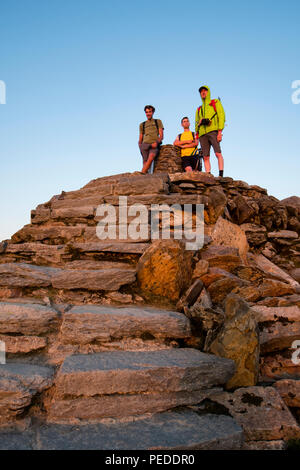 Snowdon Gipfels mit 3 Wanderer stand bewundern Sie den Sonnenuntergang. Stockfoto