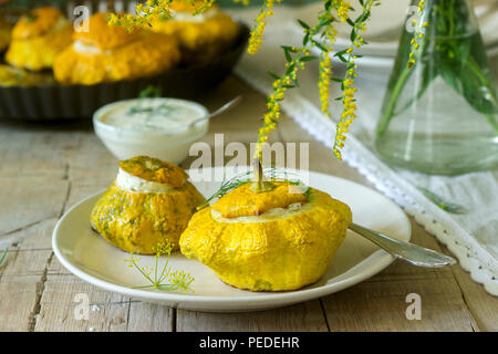 Pattypan Squash oder Kürbisse, gefüllt mit Ricotta mit Basilikum und Dill und serviert mit saurer Sahne Soße. Vegetarisches Essen, rustikaler Stil, selektiven Fokus. Stockfoto