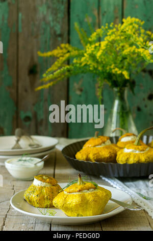 Pattypan Squash oder Kürbisse, gefüllt mit Ricotta mit Basilikum und Dill und serviert mit saurer Sahne Soße. Vegetarisches Essen, rustikaler Stil, selektiven Fokus. Stockfoto