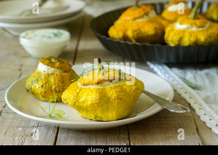 Pattypan Squash oder Kürbisse, gefüllt mit Ricotta mit Basilikum und Dill und serviert mit saurer Sahne Soße. Vegetarisches Essen, rustikaler Stil, selektiven Fokus. Stockfoto