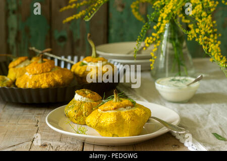 Pattypan Squash oder Kürbisse, gefüllt mit Ricotta mit Basilikum und Dill und serviert mit saurer Sahne Soße. Vegetarisches Essen, rustikaler Stil, selektiven Fokus. Stockfoto