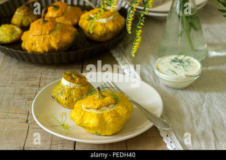 Pattypan Squash oder Kürbisse, gefüllt mit Ricotta mit Basilikum und Dill und serviert mit saurer Sahne Soße. Vegetarisches Essen, rustikaler Stil, selektiven Fokus. Stockfoto