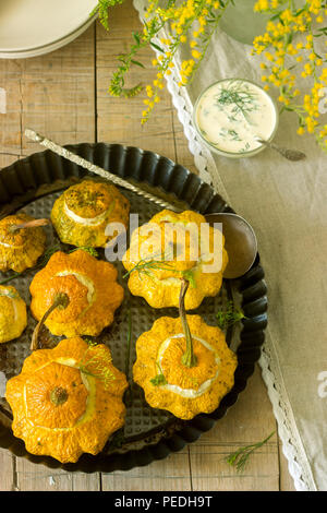 Pattypan Squash oder Kürbisse, gefüllt mit Ricotta mit Basilikum und Dill und serviert mit saurer Sahne Soße. Vegetarisches Essen, rustikaler Stil, selektiven Fokus. Stockfoto