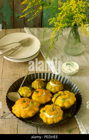 Pattypan Squash oder Kürbisse, gefüllt mit Ricotta mit Basilikum und Dill und serviert mit saurer Sahne Soße. Vegetarisches Essen, rustikaler Stil, selektiven Fokus. Stockfoto