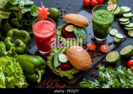 Gesund Vegan essen. Frisches Gemüse auf schwarzem Hintergrund. Detox Diät. Verschiedene bunte frische Säfte. Stockfoto