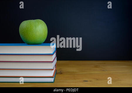 Tafel mit Bücher und Apple auf hölzernen Schreibtisch Stockfoto