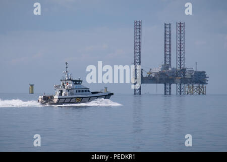 Seacat Volunteer Position zu den Atlantischen Amsterdam, in der Ferne aufgebockt Neben Offshore Umspannwerk (OSS) Z01 auf Rennen Bank Offshore Wind Farm, UK gesehen Stockfoto