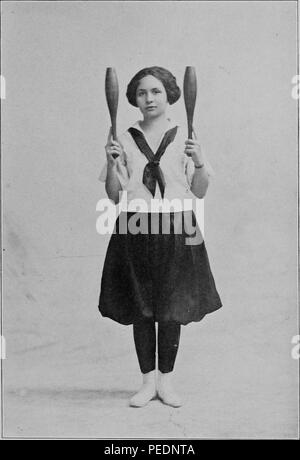Schwarz-weiß-Foto einer Schülerin, mit Blick auf den Betrachter, mit einem neutralen Ausdruck, tragen Fitness Kleidung im Viktorianischen Frauen und zwei Vereine senkrecht halten, um die grundlegende Position für die Indischen Clubs, 1922 zu illustrieren. Mit freundlicher Genehmigung Internet Archive. () Stockfoto