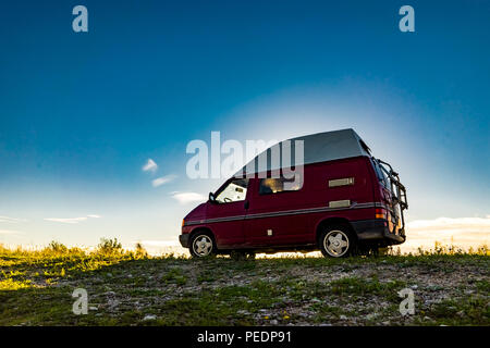 Estland - August 2018: VW Transporter T4 auf Ostsee mit Sonnenuntergang im Hintergrund und blauen Himmel mit Wolken. Der Volkswagen Transporter (T4) ist ein Van pr Stockfoto