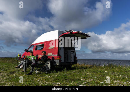 Estland - August 2018: VW Transporter T4 auf Ostsee mit Sonnenuntergang im Hintergrund und blauen Himmel mit Wolken. Im Vordergrund, Camping Ausrüstung ist eingestellt Stockfoto