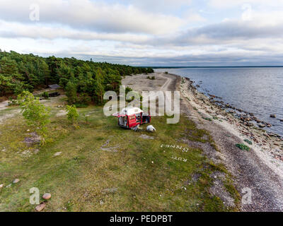 Estland - August 2018: VW Transporter T4 auf Ostsee mit Sonnenuntergang im Hintergrund und blauen Himmel mit Wolken. Im Vordergrund, Camping Ausrüstung ist eingestellt Stockfoto