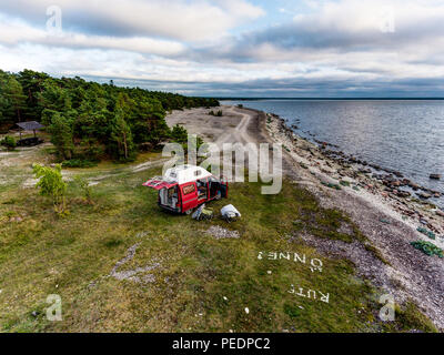 Estland - August 2018: VW Transporter T4 auf Ostsee mit Sonnenuntergang im Hintergrund und blauen Himmel mit Wolken. Im Vordergrund, Camping Ausrüstung ist eingestellt Stockfoto