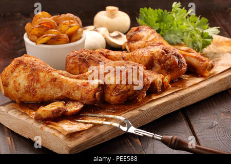 Gebratene Hähnchenschenkel mit Kartoffelchips auf hölzernen Hintergrund Stockfoto