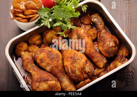 Gebratene Hähnchenschenkel mit Kartoffelchips auf hölzernen Hintergrund Stockfoto