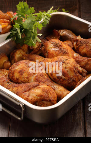 Gebratene Hähnchenschenkel mit Kartoffelchips auf hölzernen Hintergrund Stockfoto
