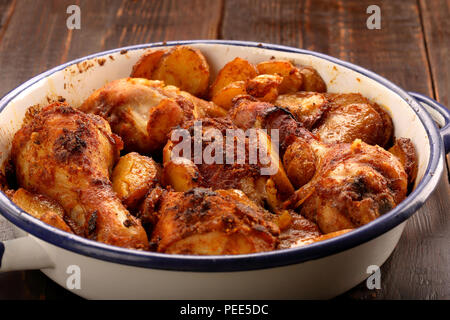 Gebratene Hähnchenschenkel mit Kartoffelchips auf hölzernen Hintergrund Stockfoto