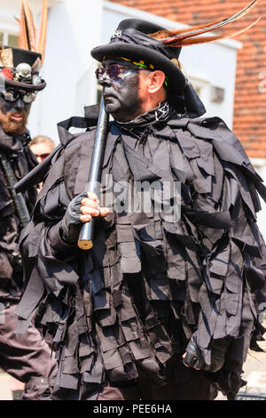 Traditionelle englische Volkstänzer, Wolfs Kopf Morris Dance Seite, in Schwarz tatter Jacken, Tanzen in der Straße am Sandwich Folk und Ale-Festival. Stockfoto