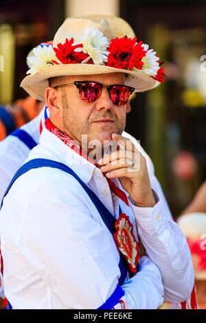 Traditionelle englische Volkstänzer aus dem Osten Kent Morris Seite. Stehen und drehte sich um, Viewer, Auge. Hut mit roten und weißen Blumen auf Stockfoto