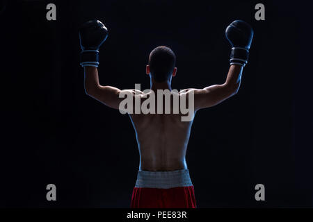 Rückansicht der Mann Boxer mit erhobenen Händen in den Sieg Geste. Konzept der harten Sport, Ruhm und Erfolg. Stockfoto