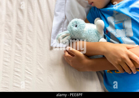 Kleinen Jungen schlafen im Bett und hielt seinen Bunny robbit. Stockfoto