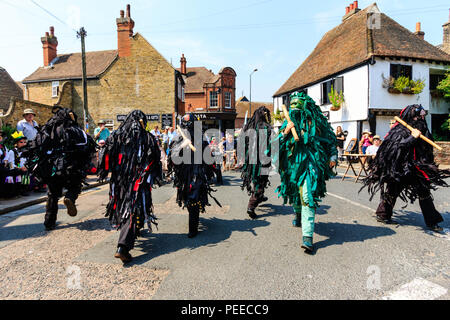 Traditionelle englische Volkstänzer, die Wilde Jagd Morris Dance Seite, in Schwarz tatter Jacken, Tanzen auf der Straße am Sandwich Folk und Ale-Festival. Stockfoto