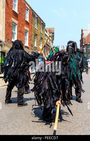 Traditionelle englische Volkstänzer, die Wilde Jagd Morris Dance Seite, in Schwarz tatter Jacken, Tanzen auf der Straße am Sandwich Folk und Ale-Festival. Stockfoto